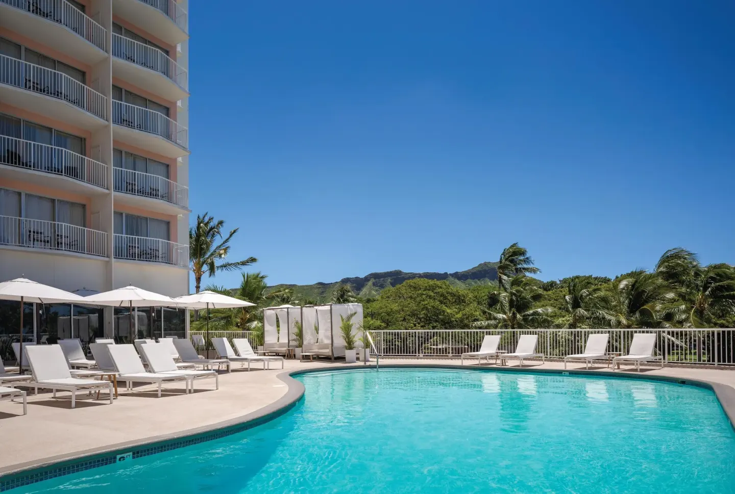 Outdoor pool with loungers and blue sky at Park Shore Waikiki.