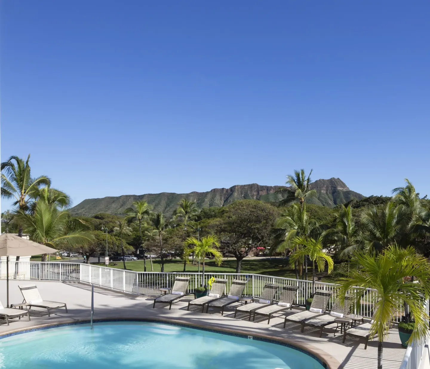Pool deck with lounge chairs and mountain view at Park Shore Waikiki.