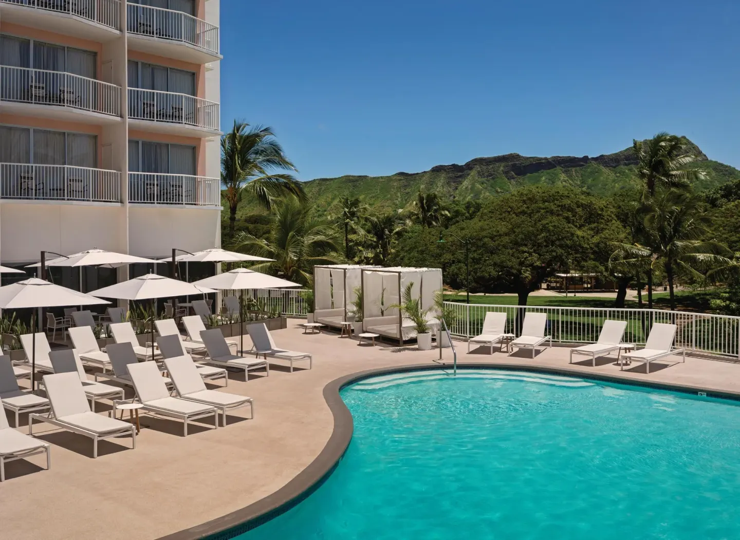 Pool with loungers, umbrellas, and hotel balconies at Park Shore Waikiki.