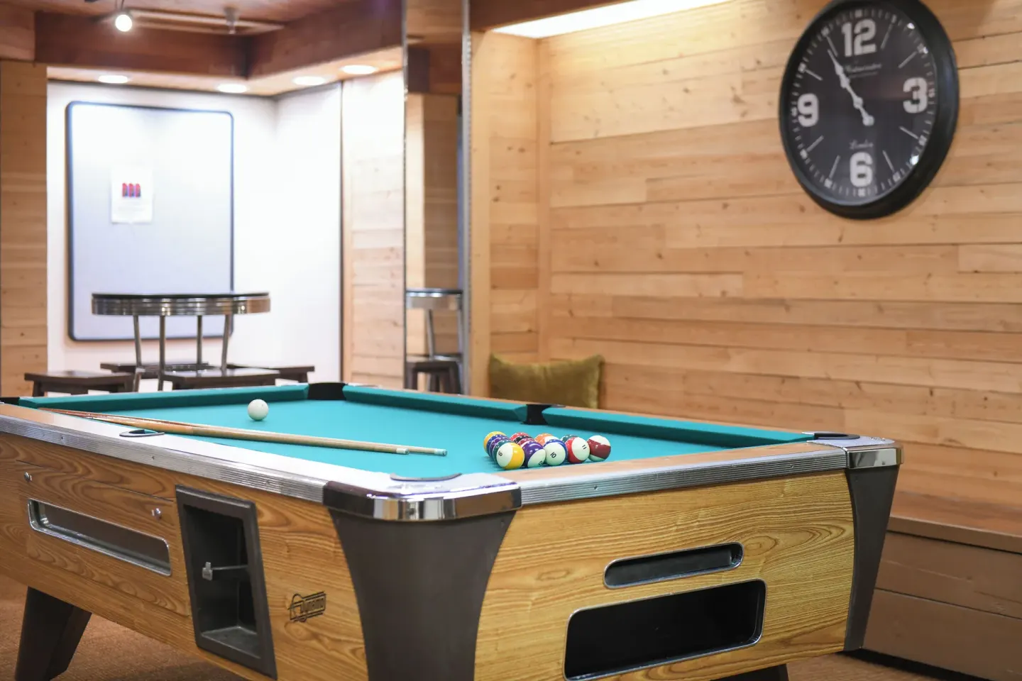 Recreation room with a pool table, wall clock, and wood paneling at Park Shore Waikiki.