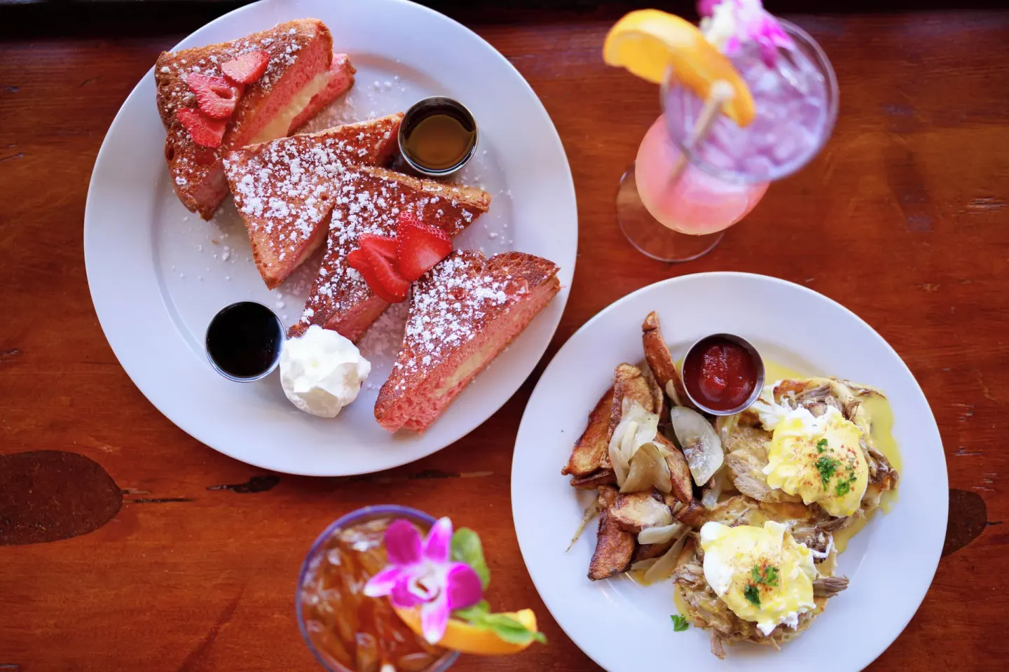 French toast, eggs, and tropical drinks on a wooden table at Park Shore Waikiki.