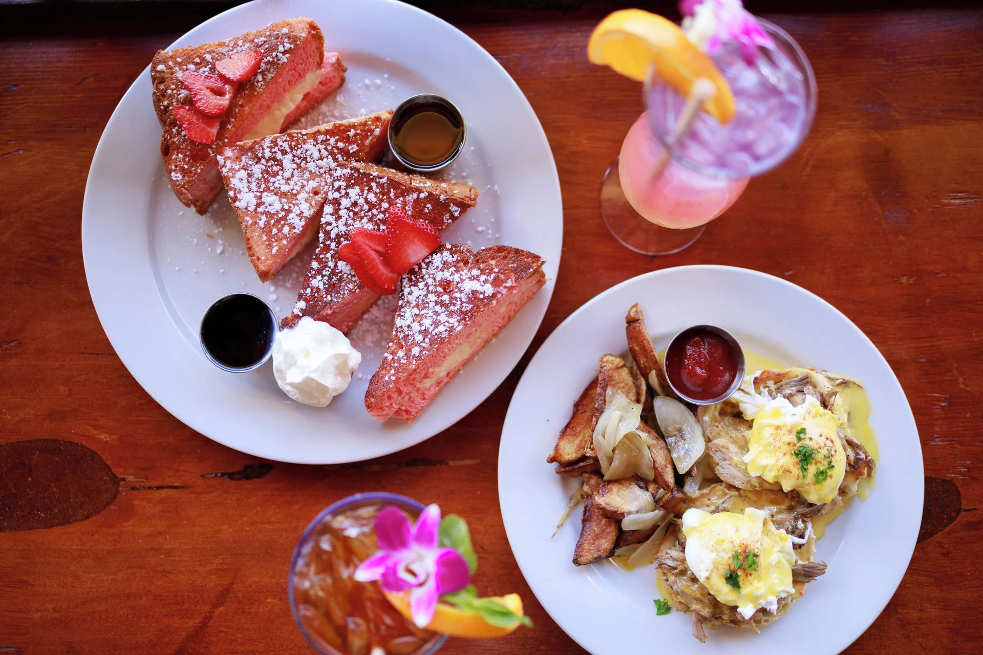 French toast, eggs, and tropical drinks on a wooden table at Park Shore Waikiki.