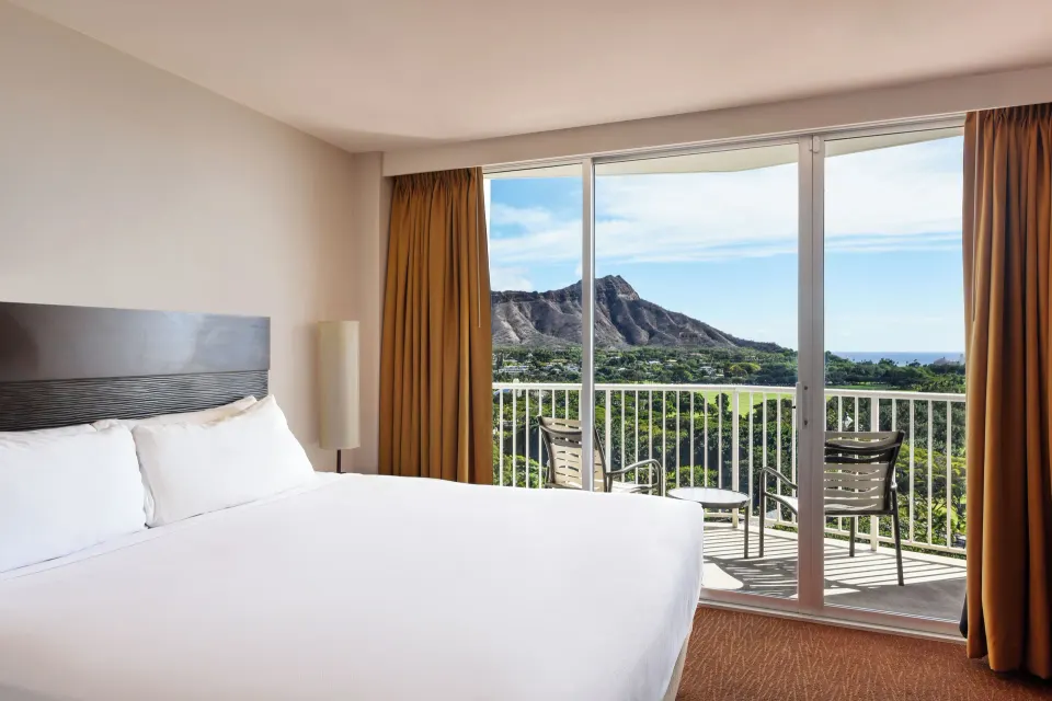 King bed beside balcony doors in a Premier Ocean View room at Park Shore Waikiki.