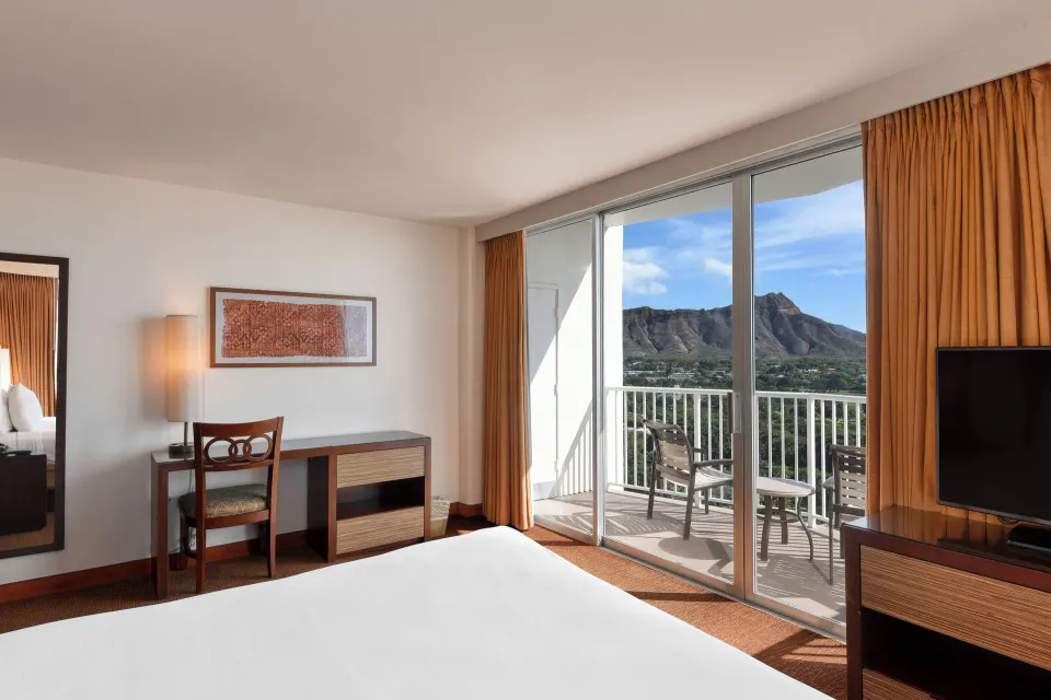 Corner guest room with king bed, desk, TV, and Diamond Head balcony view at Park Shore Waikiki.