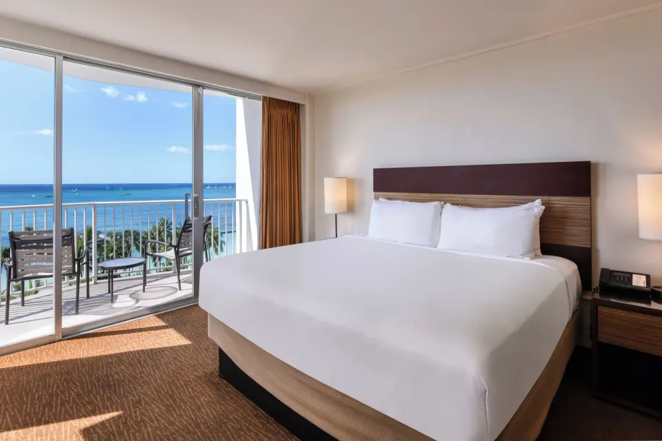 King-bedded Ocean View room with balcony seating at Park Shore Waikiki.