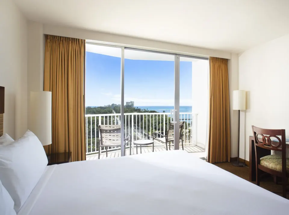 Ocean View room with bed, desk chair, and balcony at Park Shore Waikiki.