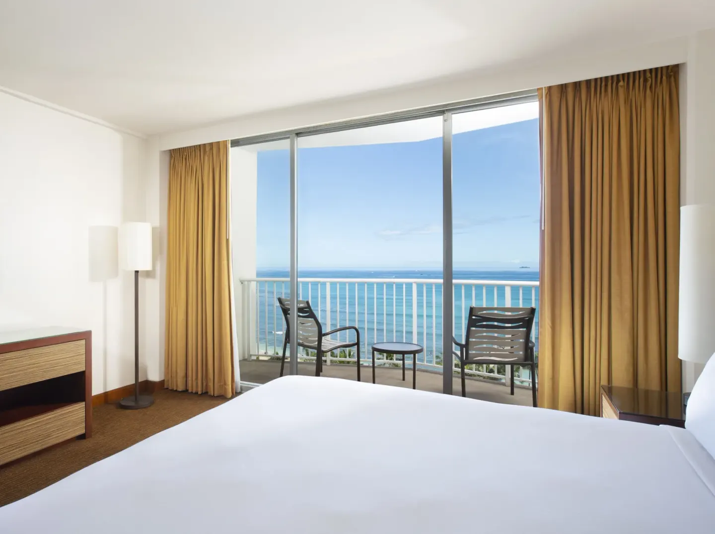 Oceanfront room with king bed, balcony seating, and ocean view at Park Shore Waikiki.