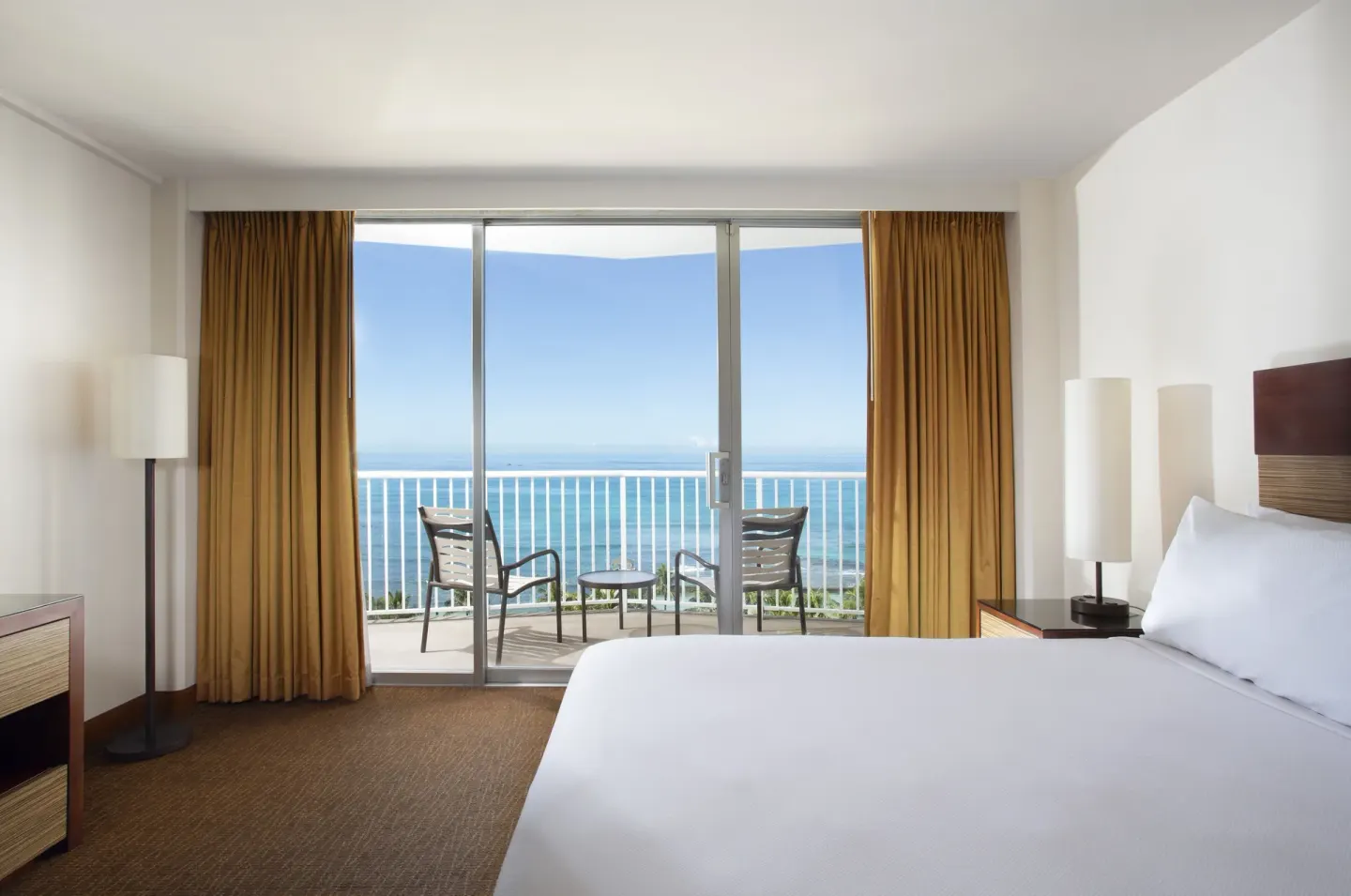 Oceanfront room with king bed and balcony seating overlooking the ocean at Park Shore Waikiki.