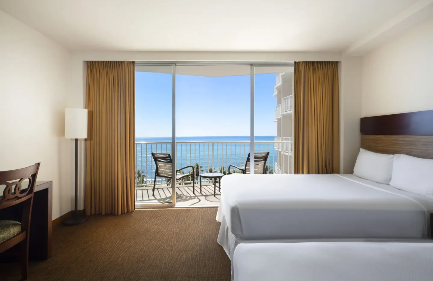 Oceanfront room with two beds, balcony chairs, and ocean view at Park Shore Waikiki.