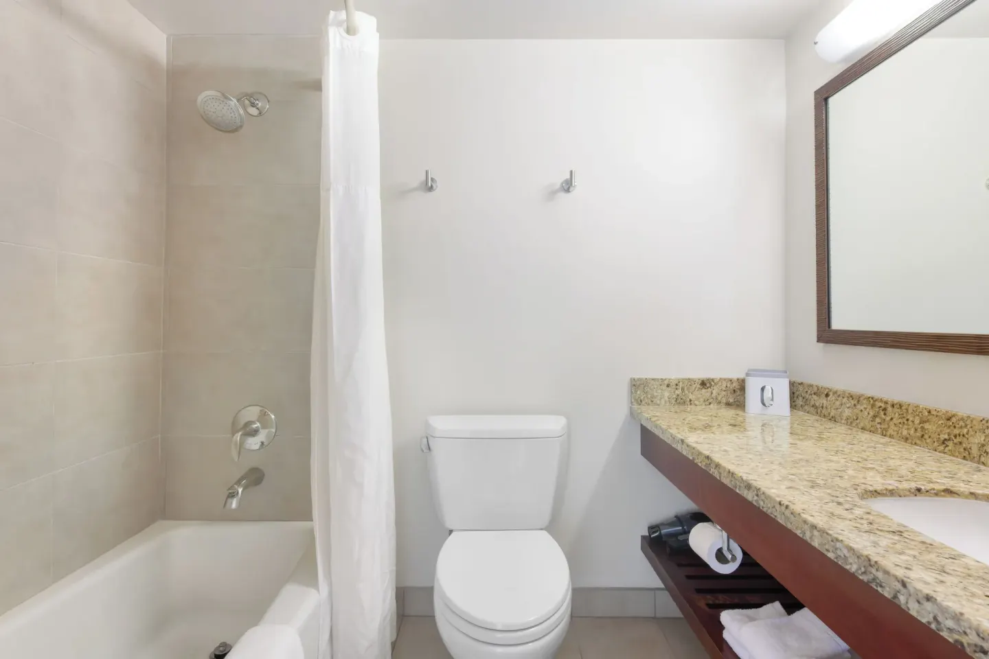 Guest bathroom with tub, shower curtain, toilet, and vanity at Park Shore Waikiki.