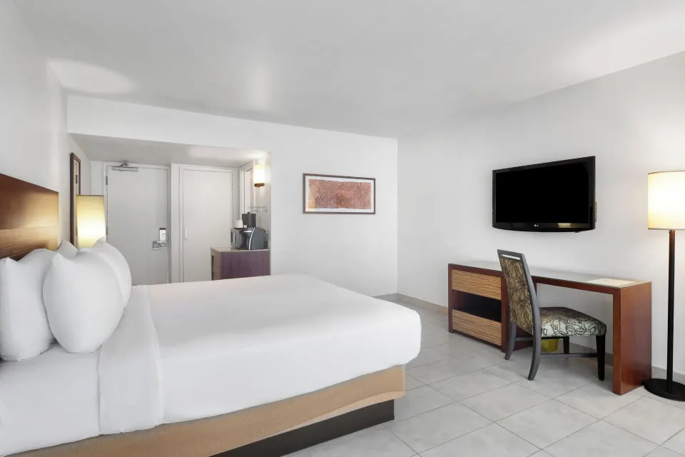 King bed guest room with desk and wall-mounted TV at Park Shore Waikiki.
