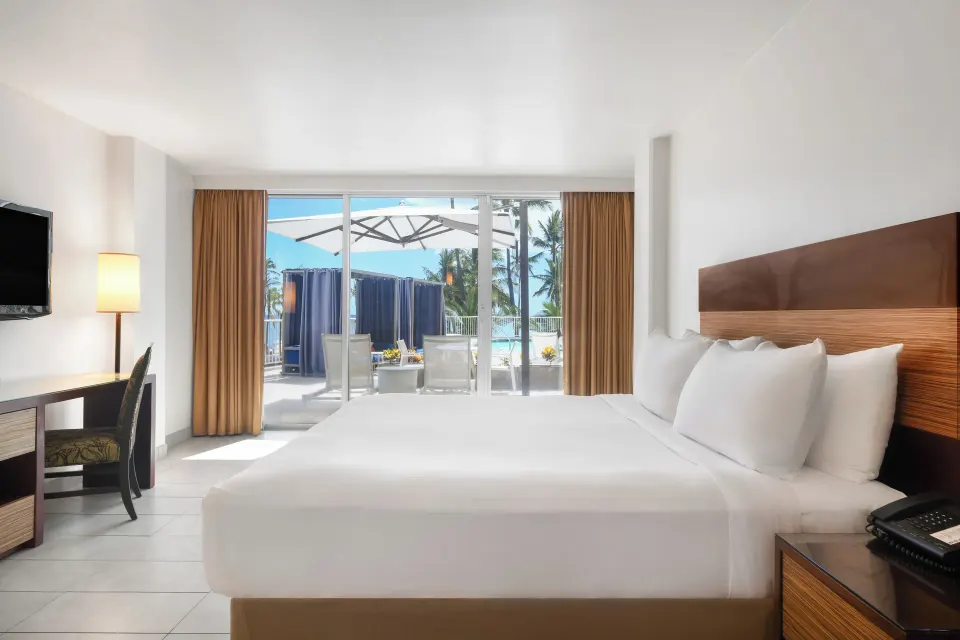 Poolside king bed guest room with lanai doors at Park Shore Waikiki.