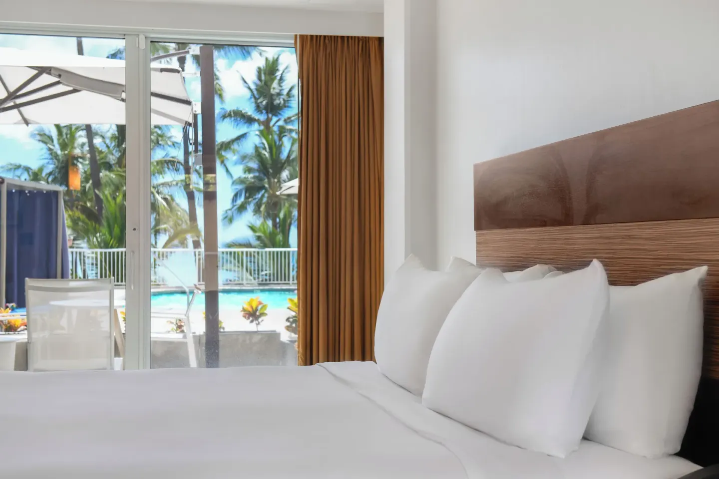 King bed beside pool-facing sliding doors at Park Shore Waikiki.