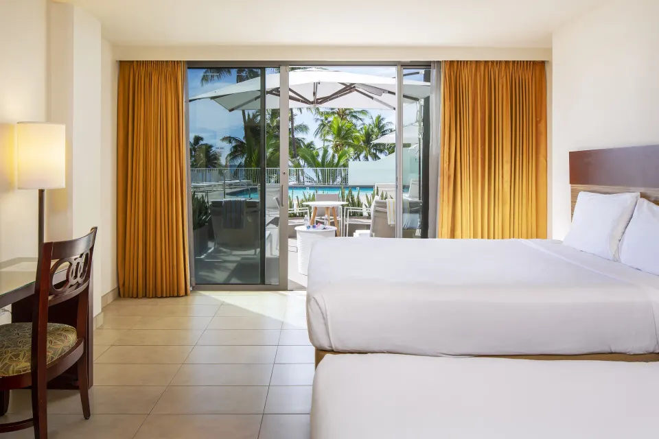 Poolside guest room with two beds and sliding lanai doors at Park Shore Waikiki.