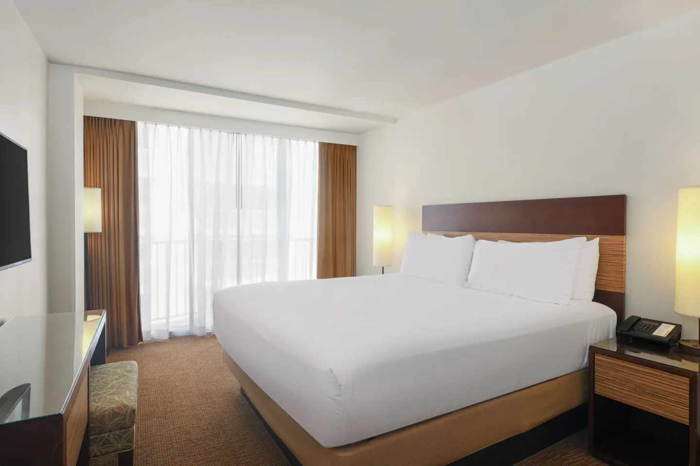 Standard Room with king bed, balcony curtains, desk, and TV at Park Shore Waikiki.
