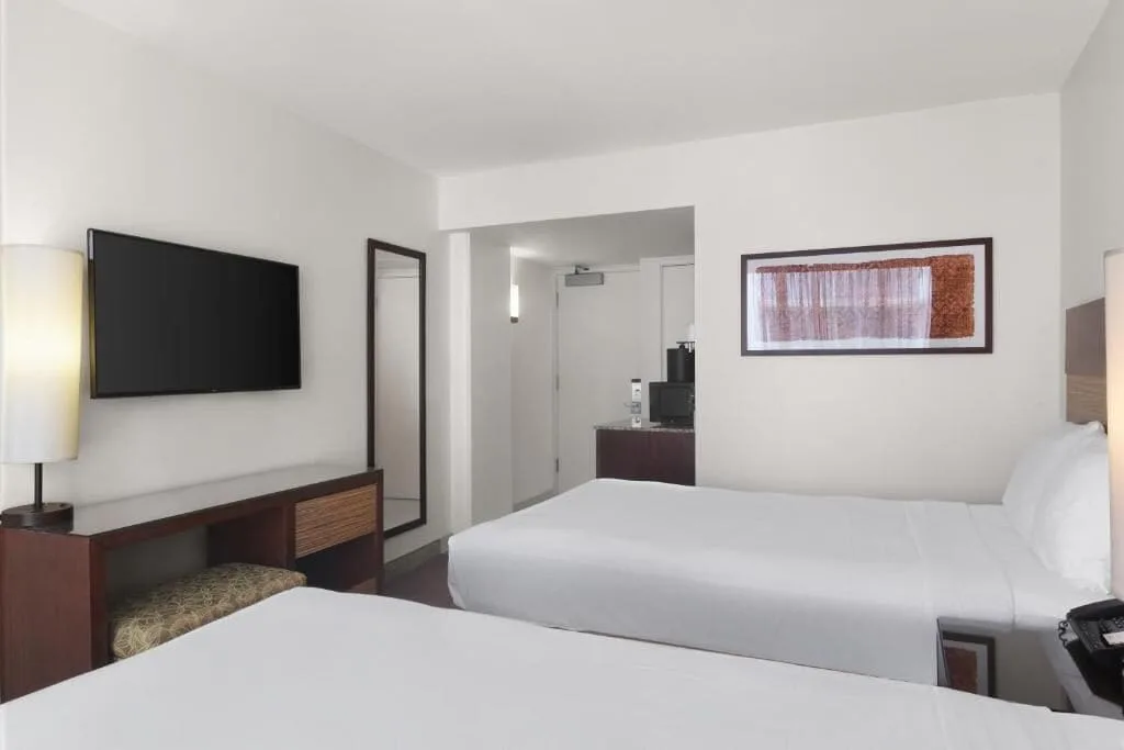 Standard Room with two beds, wall-mounted TV, mirror, artwork, and entry area at Park Shore Waikiki.
