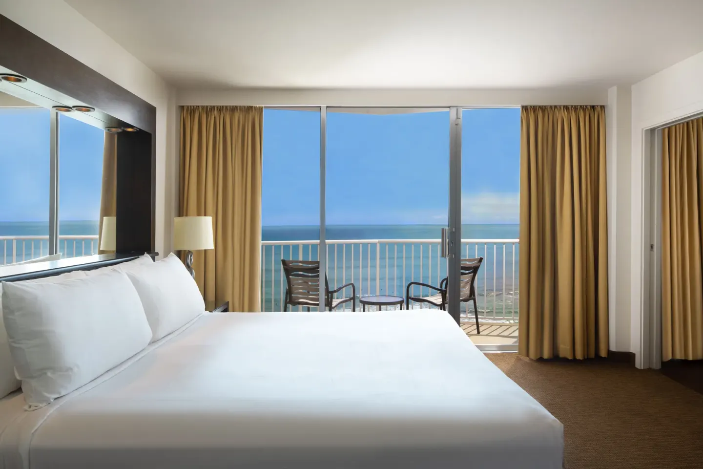 King bed in an oceanfront one-bedroom suite with balcony view at Park Shore Waikiki.