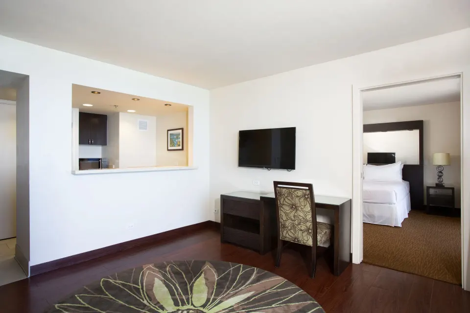 One-bedroom suite living area with desk and bedroom doorway at Park Shore Waikiki.