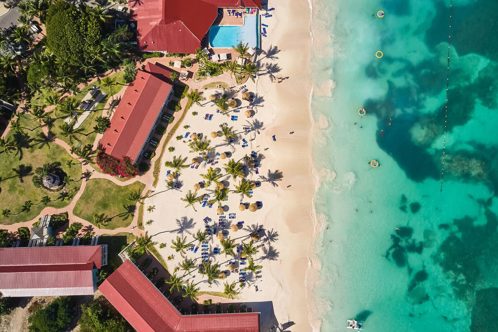 Aerial view of beach, pool, palms, and turquoise water at Pineapple Beach Club Antigua.