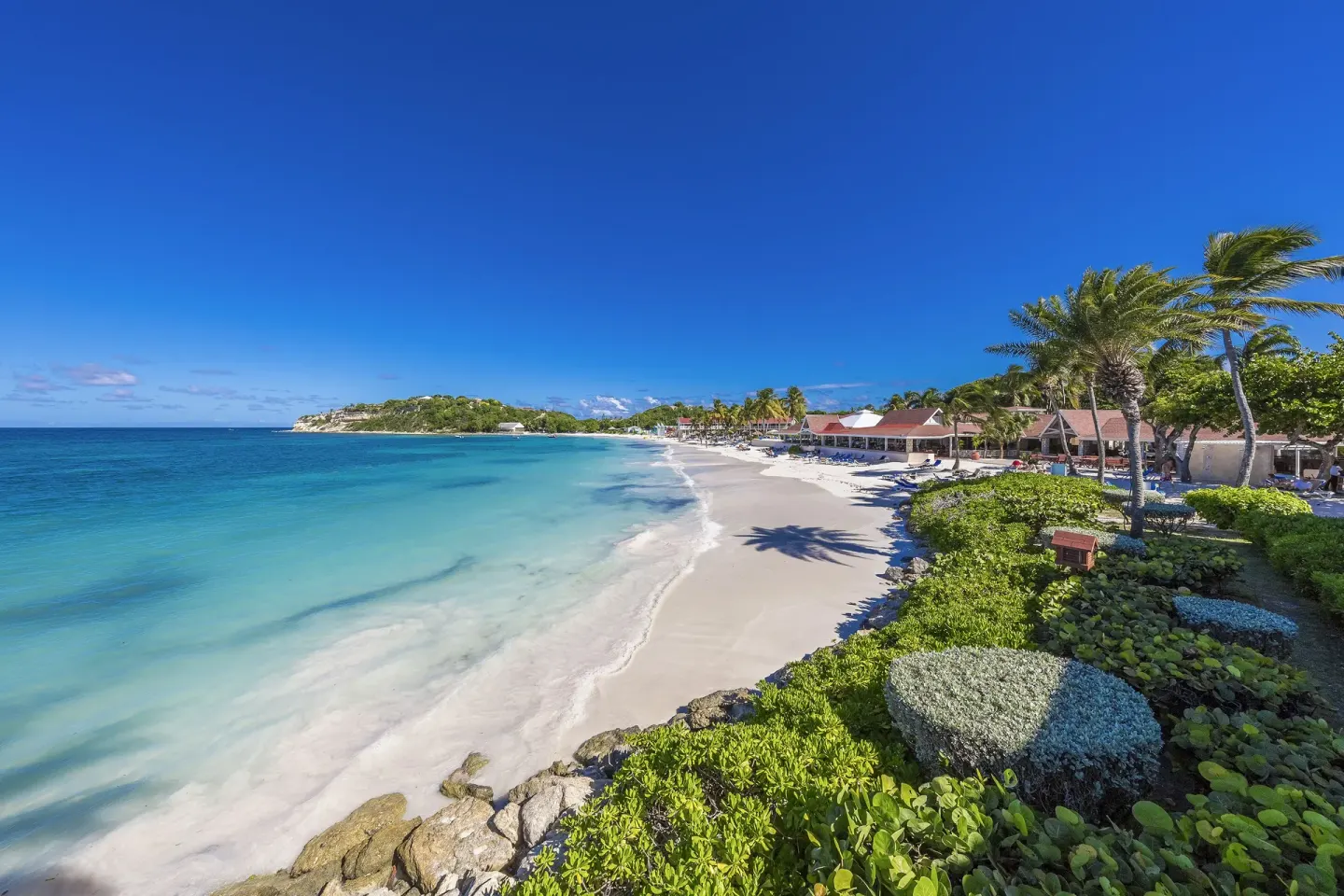 Wide beach view with turquoise water and resort buildings at Pineapple Beach Club Antigua.