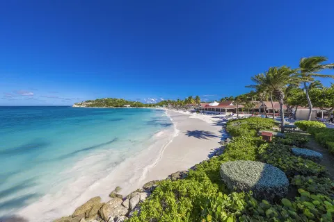 Wide beach view with turquoise water and resort buildings at Pineapple Beach Club Antigua.
