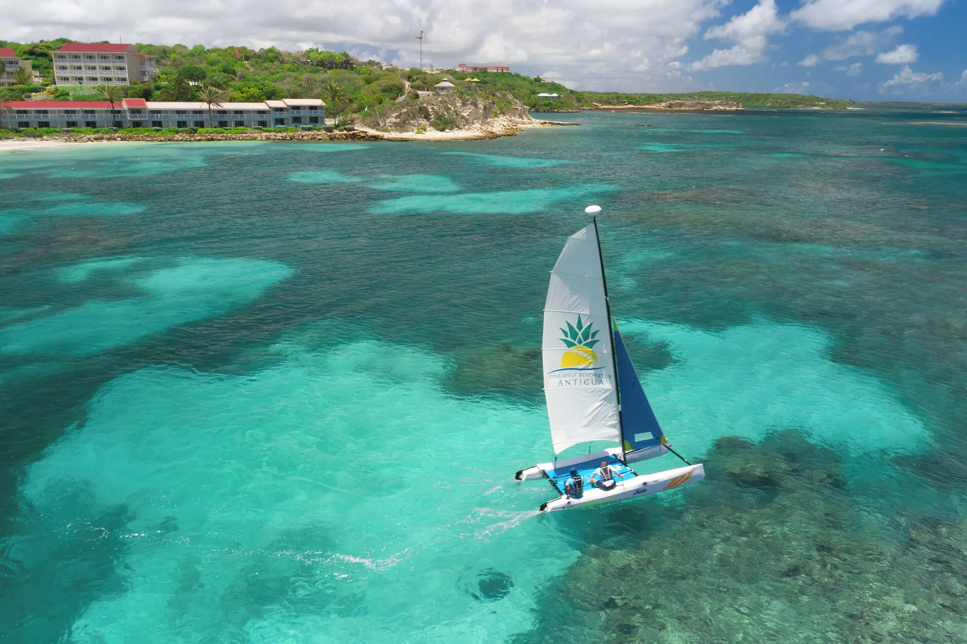 A sailboat glides over turquoise water near Pineapple Beach Club Antigua.