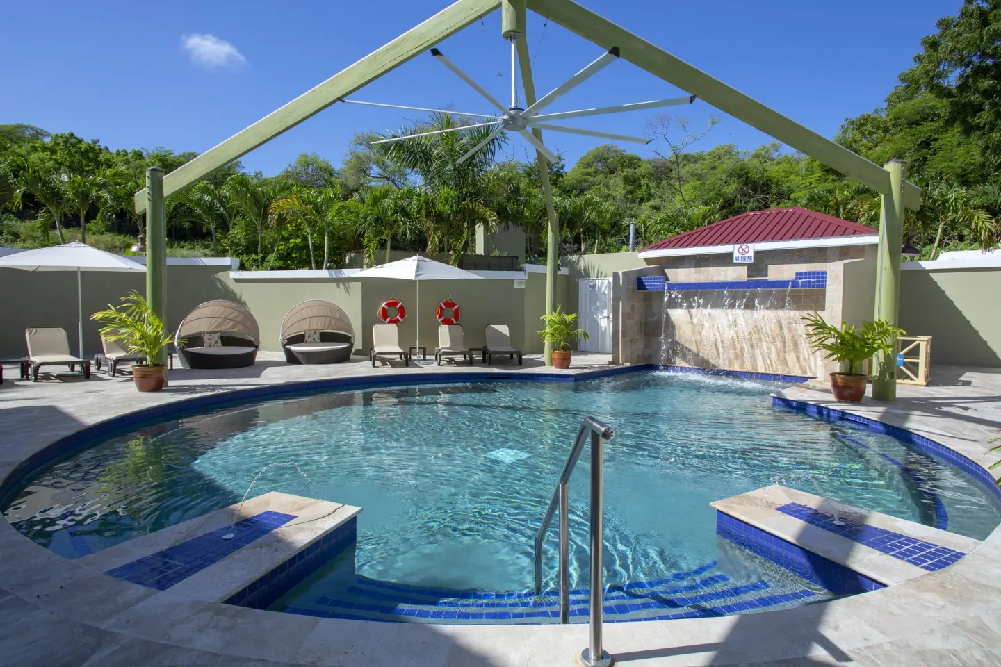 Courtyard pool with cabanas and a waterfall at Pineapple Beach Club Antigua.