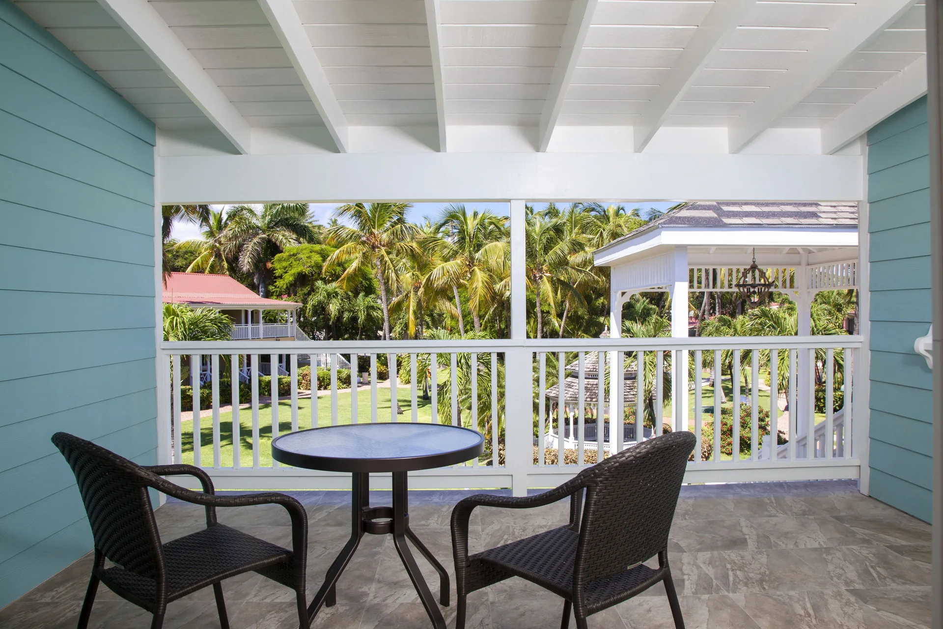 Covered balcony with two chairs and garden view at Pineapple Beach Club Antigua.