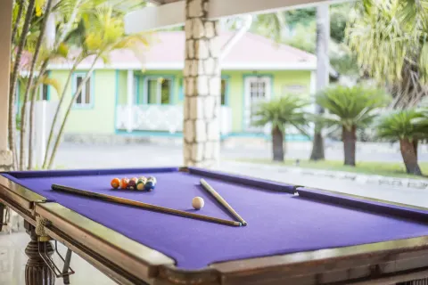 A purple-felt pool table sits in a covered game area at Pineapple Beach Club Antigua.