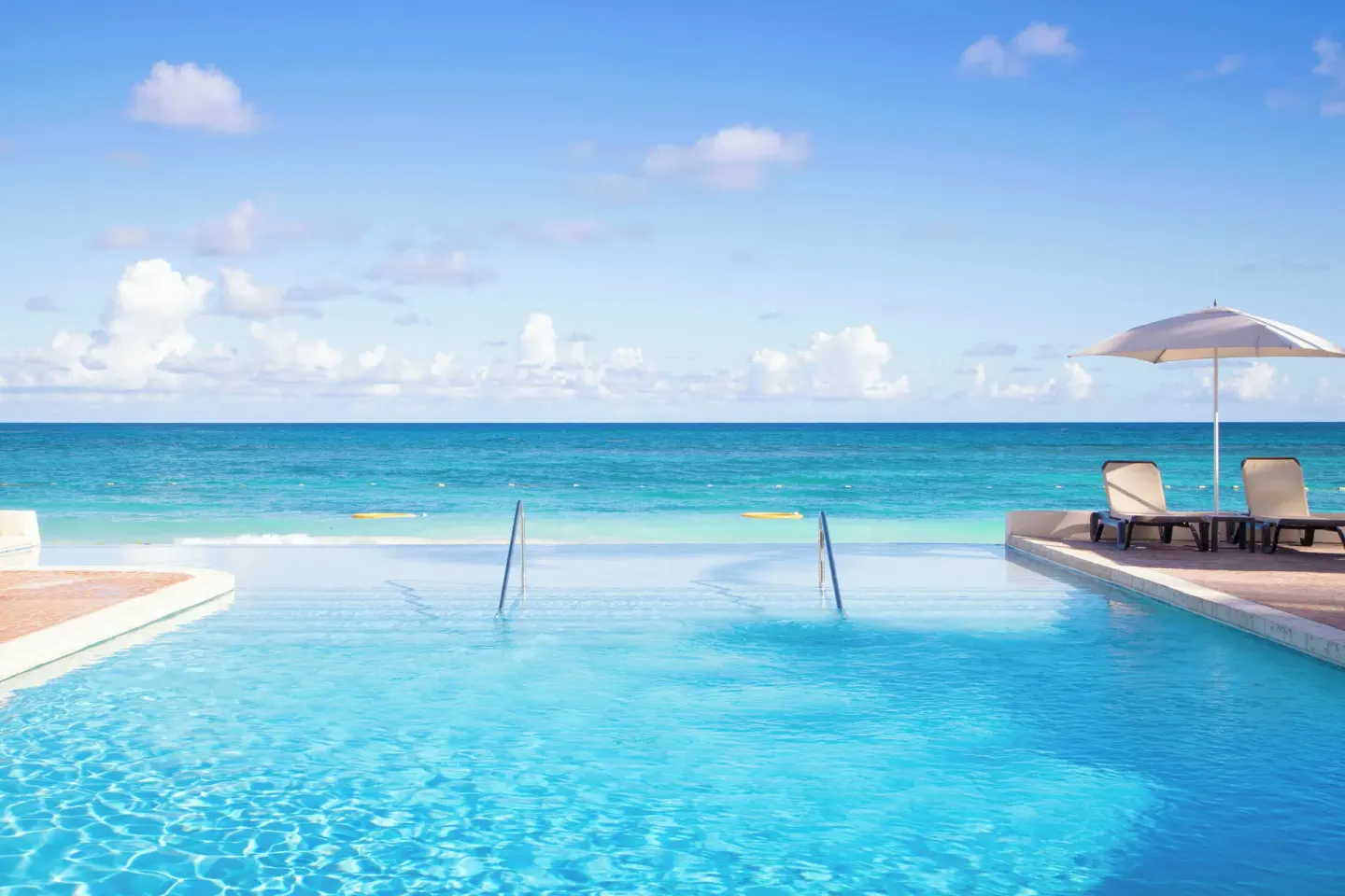Infinity pool edge facing the turquoise sea at Pineapple Beach Club Antigua.