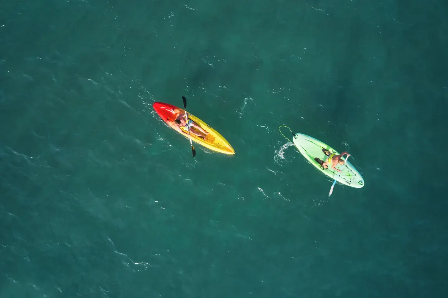 Two kayaks paddle across open water at Pineapple Beach Club Antigua.