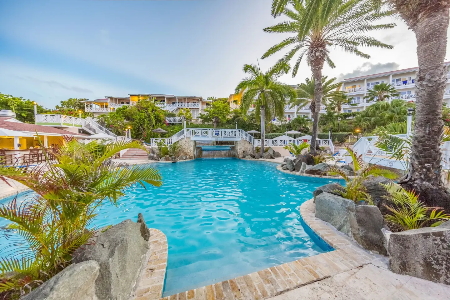 Main pool with palms and hillside rooms at Pineapple Beach Club Antigua.