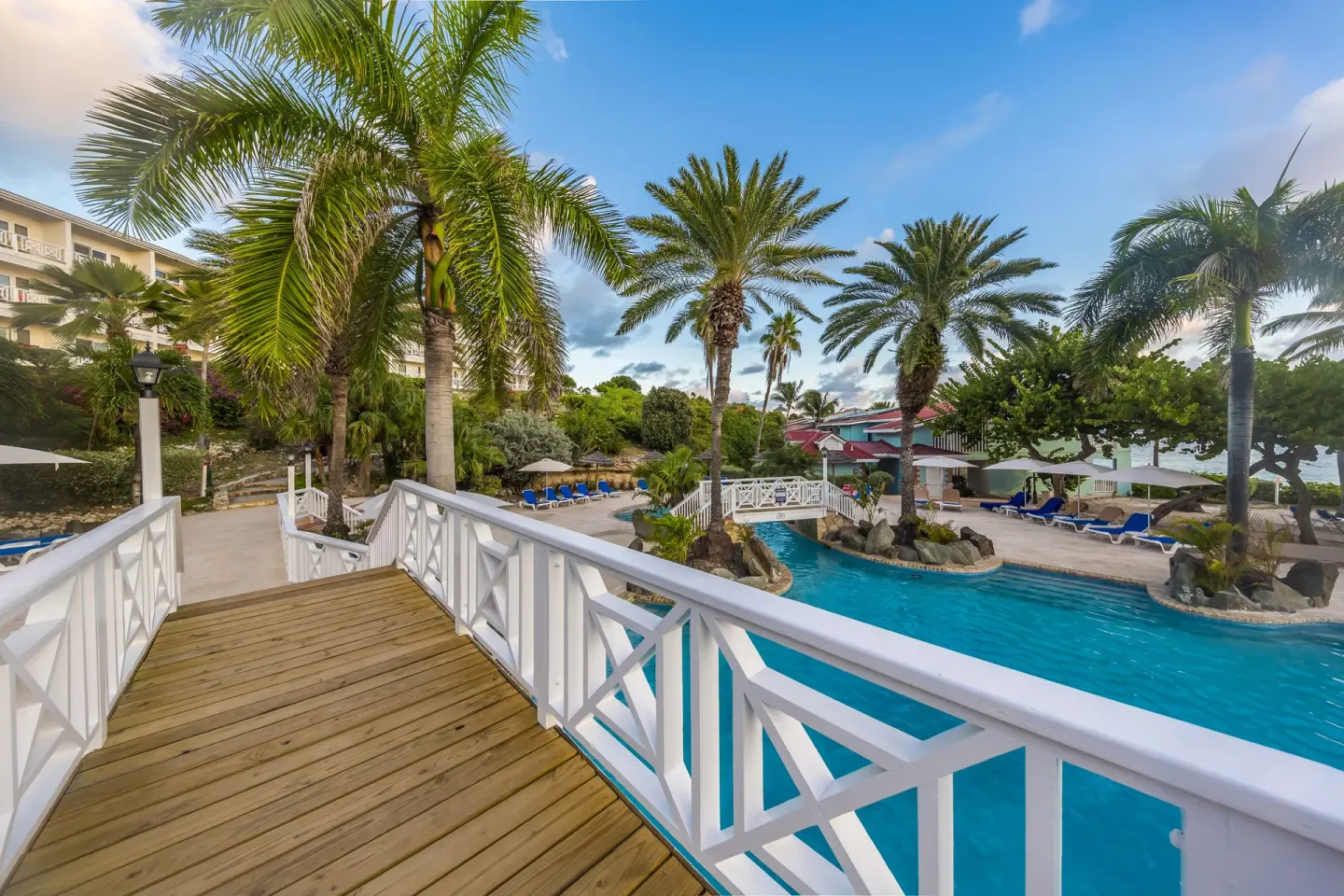 Palm-lined pool area and white footbridge at Pineapple Beach Club Antigua.