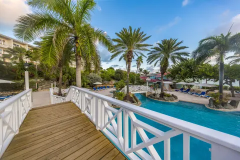 Palm-lined pool area and white footbridge at Pineapple Beach Club Antigua.