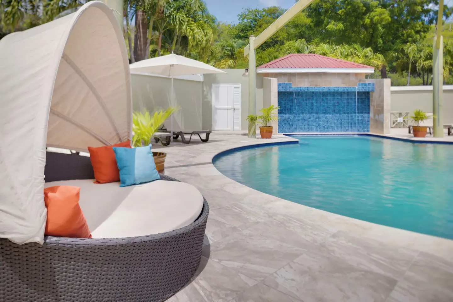 Poolside daybed and waterfall feature at Pineapple Beach Club Antigua.