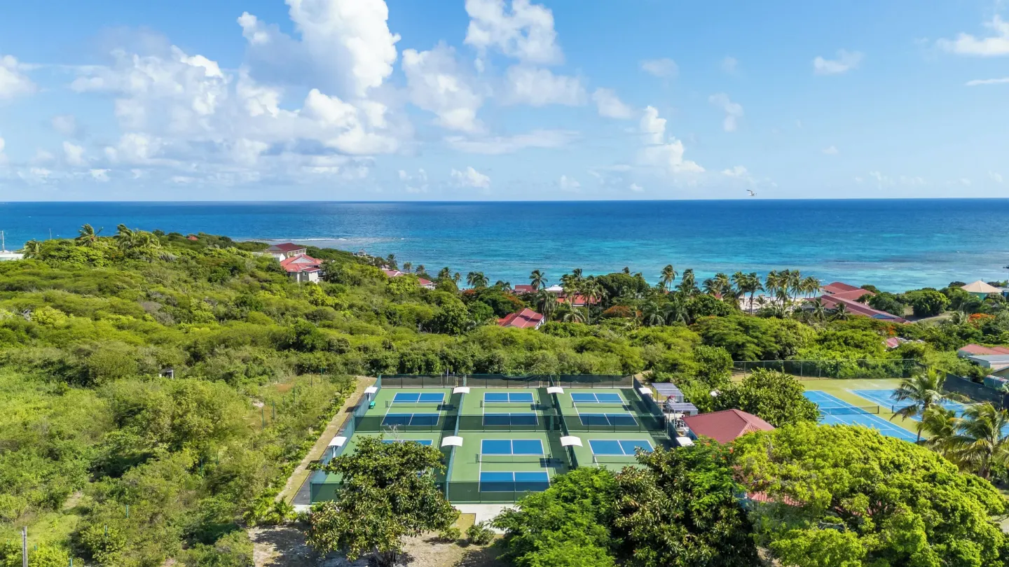 Aerial view of tennis courts and ocean at Pineapple Beach Club Antigua.