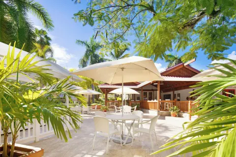 Umbrella-shaded patio seating surrounded by tropical plants at Pineapple Beach Club Antigua.