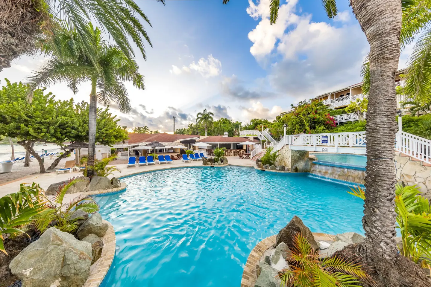 Tropical resort pool with palms and a small waterfall at Pineapple Beach Club Antigua.