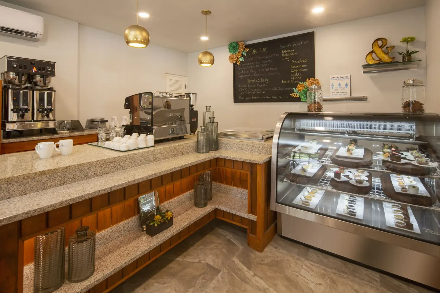 Café counter with coffee equipment and a pastry case at Pineapple Beach Club Antigua.