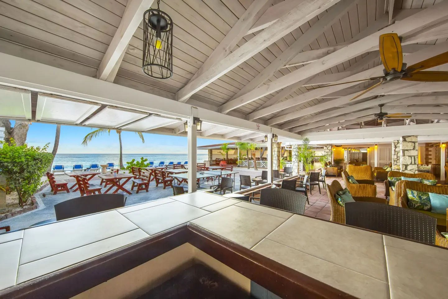 Covered beachfront bar and lounge with ocean views at Pineapple Beach Club Antigua.