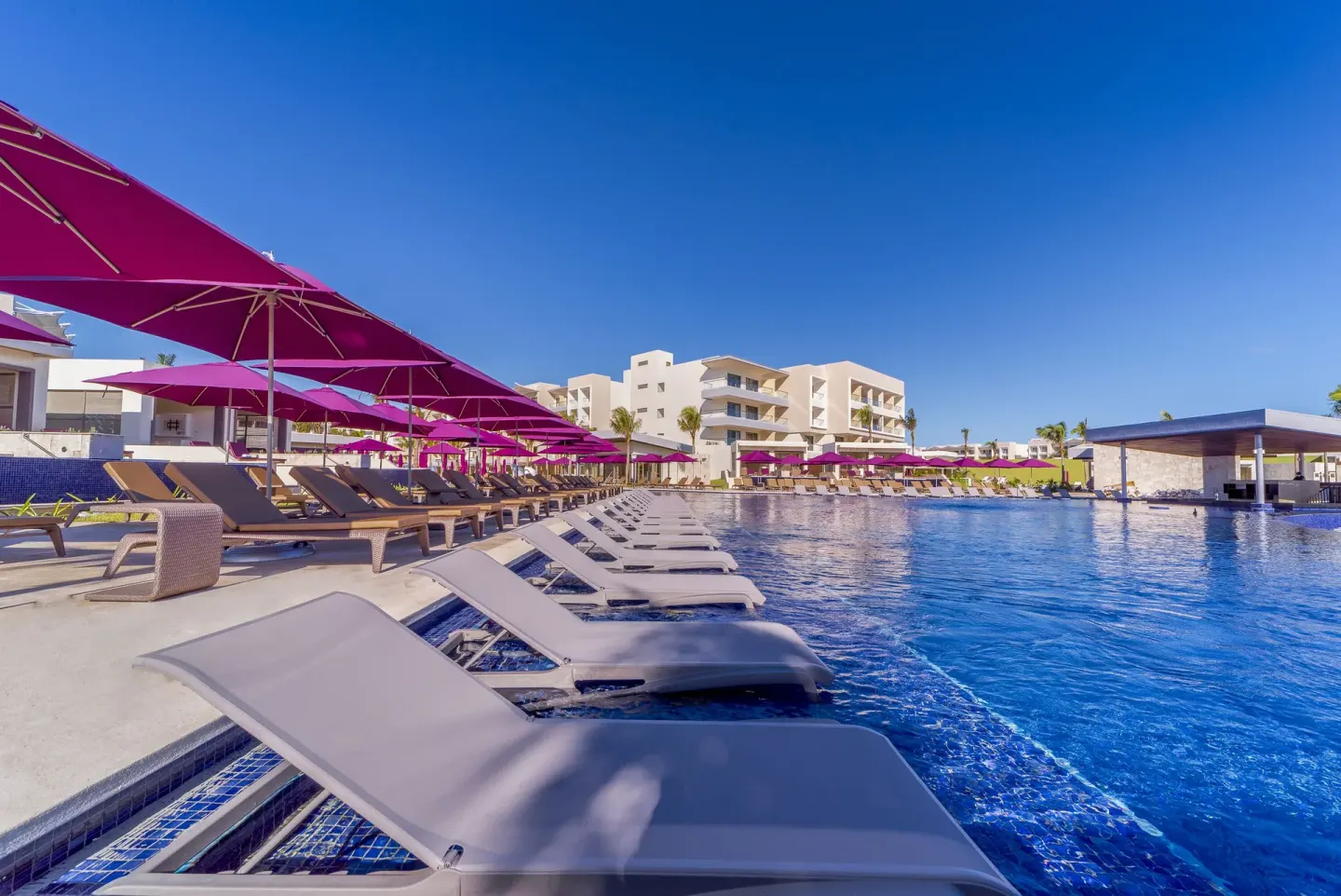 In-water loungers and purple umbrellas around a large pool at Planet Hollywood Cancun.
