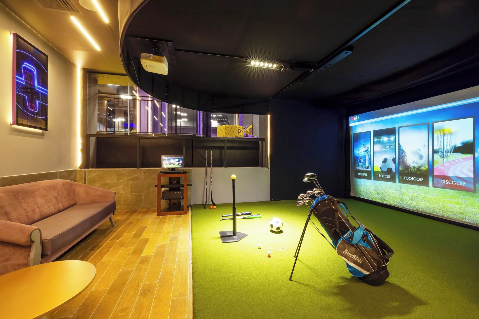 Indoor sports simulator with golf clubs, turf, and screen at Planet Hollywood Cancun.