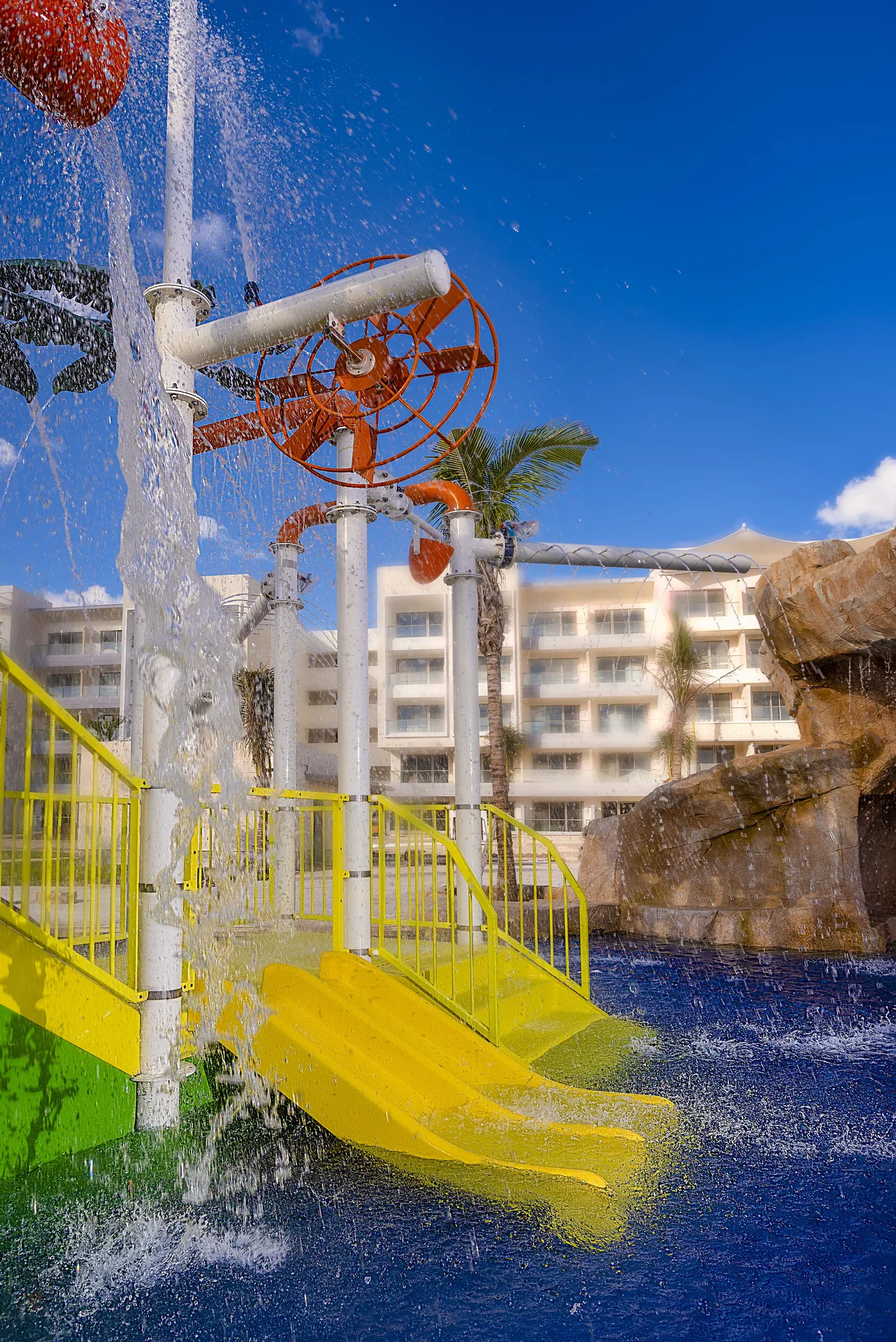 Colorful splash pad with slides and water sprays at Planet Hollywood Cancun.