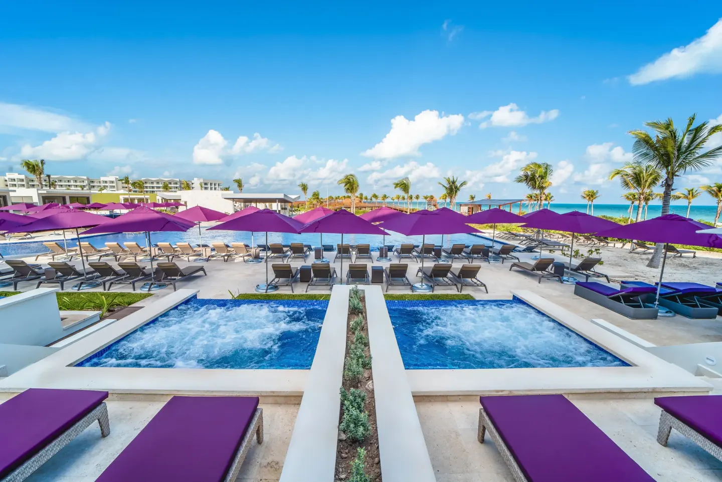 Symmetrical pool area with hot tubs and purple umbrellas at Planet Hollywood Cancun.
