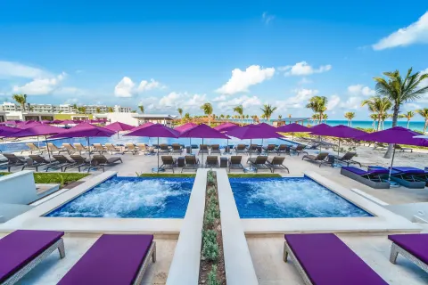 Symmetrical pool area with hot tubs and purple umbrellas at Planet Hollywood Cancun.