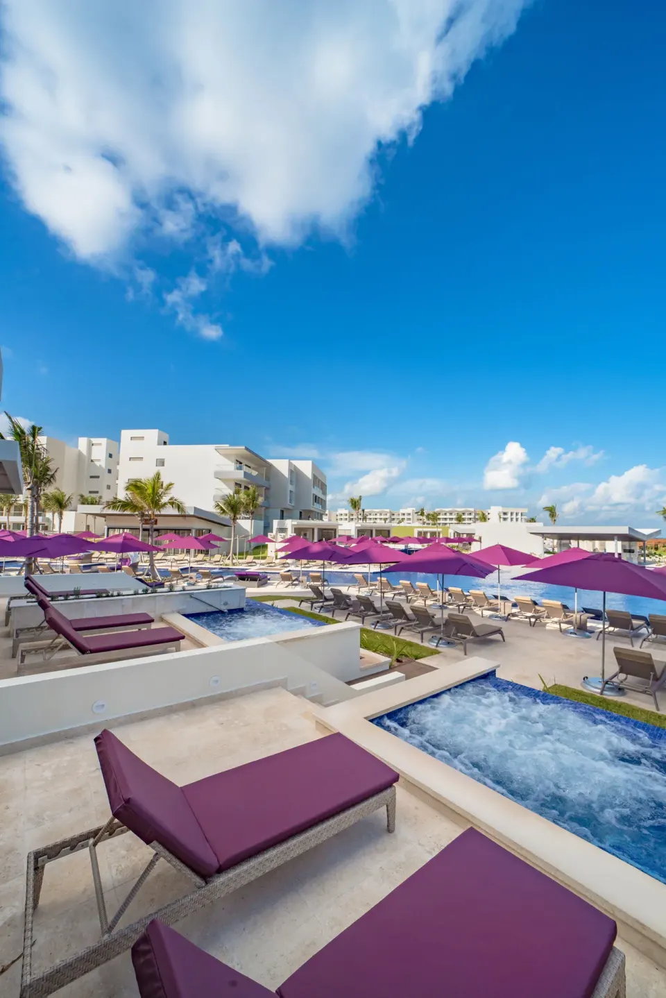 Pool deck with purple loungers and umbrellas at Planet Hollywood Cancun.