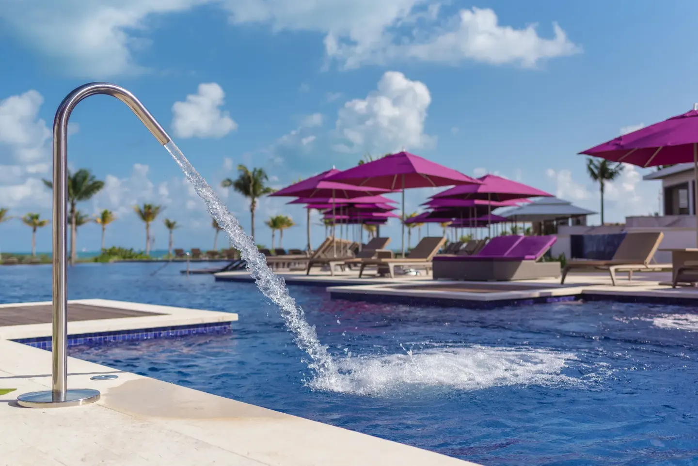 Curved pool fountain pouring into the water at Planet Hollywood Cancun.