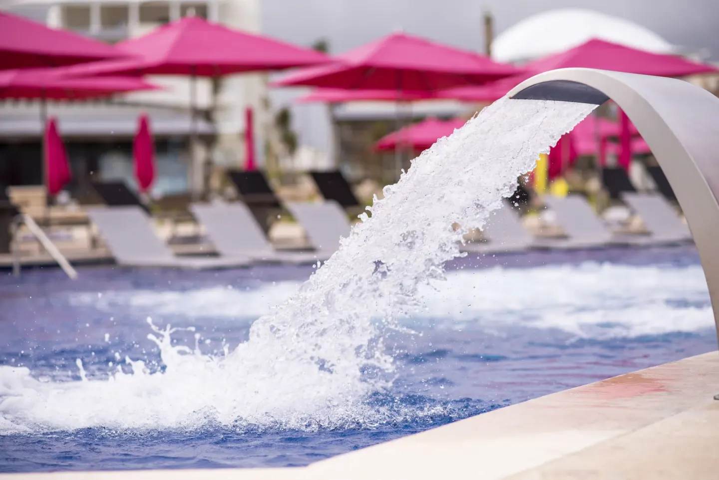 Curved water feature pouring into the pool at Planet Hollywood Cancun.