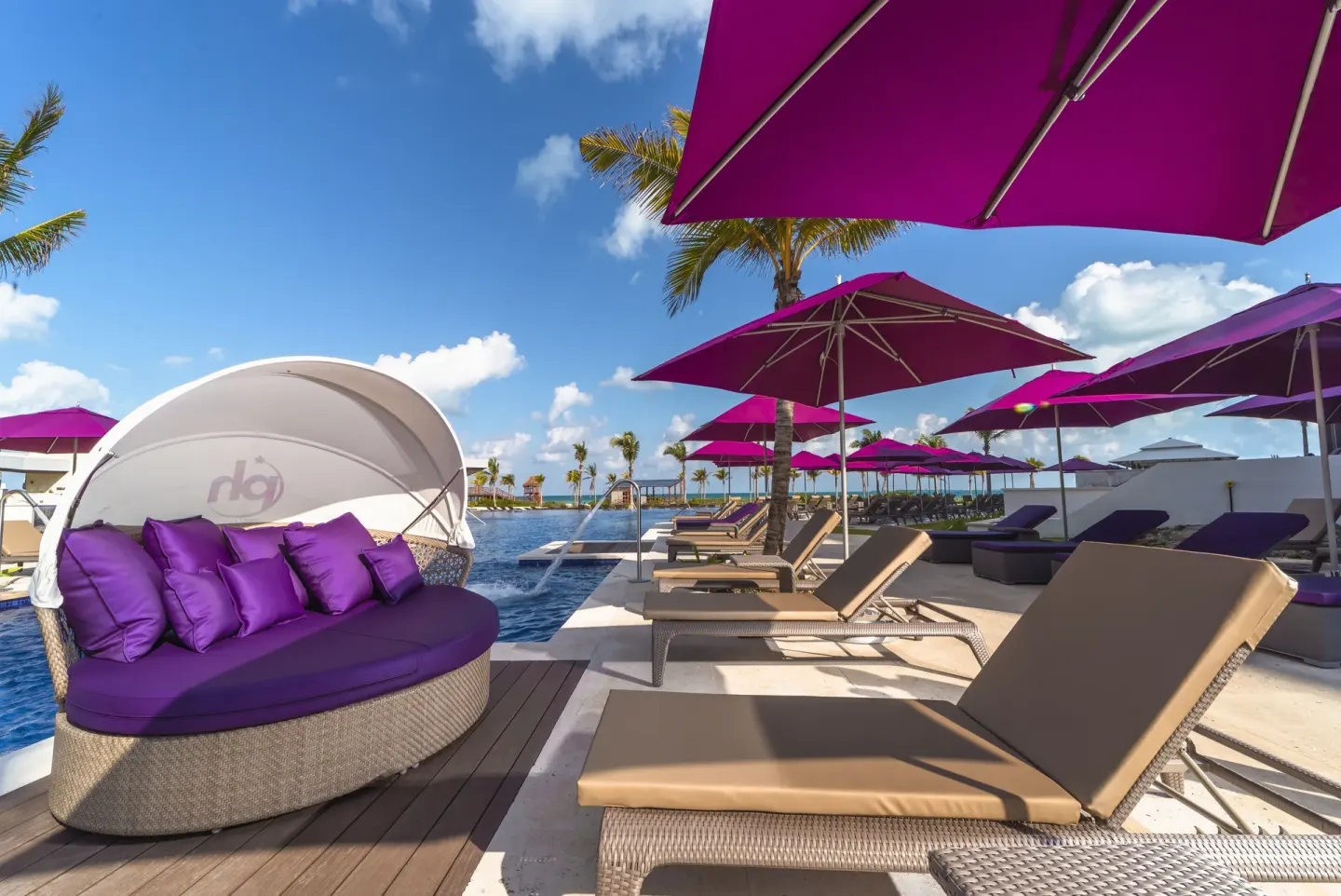 Round shaded daybed and pool loungers with purple umbrellas at Planet Hollywood Cancun.