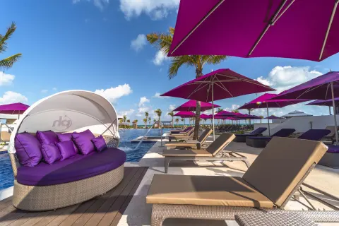 Round shaded daybed and pool loungers with purple umbrellas at Planet Hollywood Cancun.